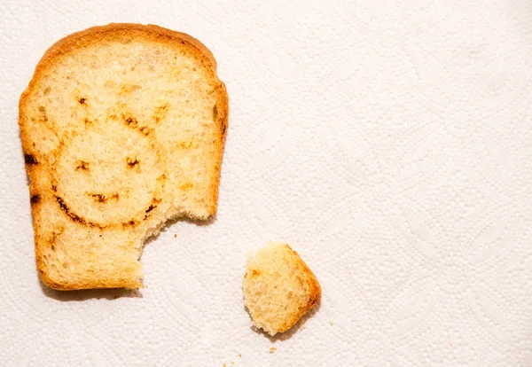 A piece of toast bread on a paper towel with smiling sun.