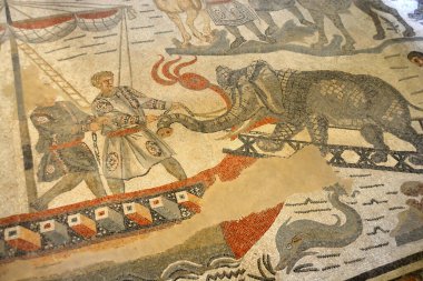 Antik Roma mozaik sahnesinde Romalılar bir fili Büyük Av Koridorunda zincirle bir nakliye gemisine çekiyor. UNESCO listesinden Villa Romana del Casale, Sicilya