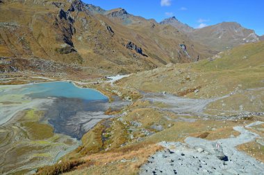 Güneşli bir günde ilginç renklerle dağlarda göl