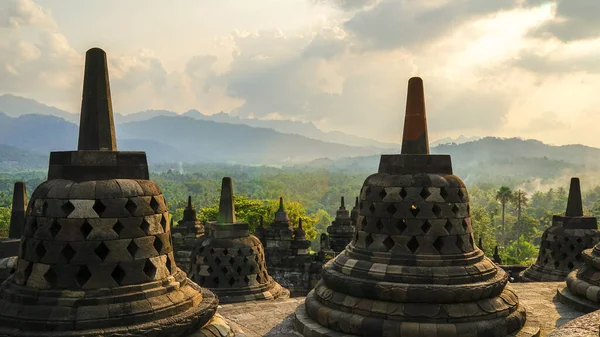 印度尼西亚东爪哇的博罗布杜尔神庙 夕阳西下 高山上的蓝天和橙色天空 绿色丛林和杜塔 旅游目的地 教科文组织世界遗产 图库图片