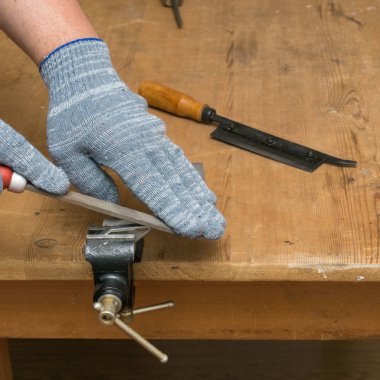 İşçi metal bir parça testereleri. Öğeyi mengeneye sabitlenmiş.