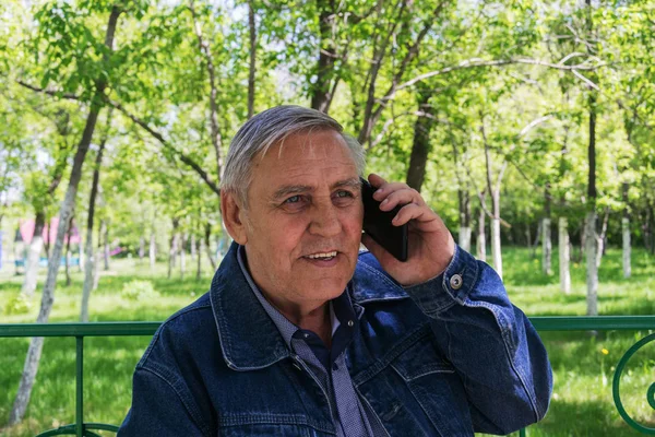 Elderly man with a phone in the park.