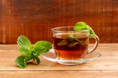 Cam bardakta naneli çay. Bir fincan ve bir masaya nane yaprakları.