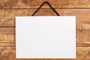 Tahta bir duvardaki ayakkabı bağına asılı boş bir kağıt parçası.