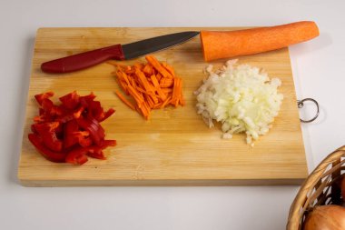 Tahta tahtada taze kırmızı biber, havuç, soğan ve bıçak var.,