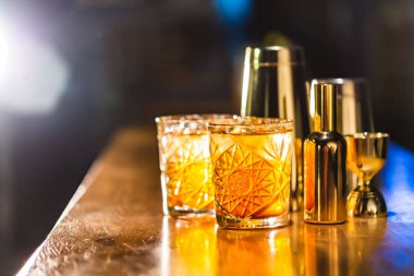 Üç renkli kokteyller büyük gözlüklü bir klasik bar ortamı içinde belgili tanımlık geçmiş bulanık içki şişeleri düzinelerce.