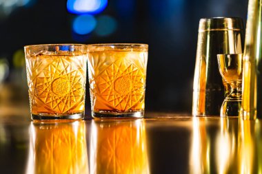 Üç renkli kokteyller büyük gözlüklü bir klasik bar ortamı içinde belgili tanımlık geçmiş bulanık içki şişeleri düzinelerce.