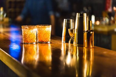 Üç renkli kokteyller büyük gözlüklü bir klasik bar ortamı içinde belgili tanımlık geçmiş bulanık içki şişeleri düzinelerce.