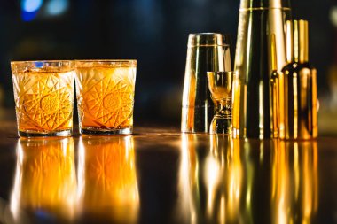 Üç renkli kokteyller büyük gözlüklü bir klasik bar ortamı içinde belgili tanımlık geçmiş bulanık içki şişeleri düzinelerce.