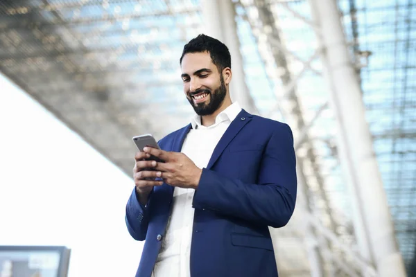 Airport man on smart phone at gate waiting in terminal. Air travel concept with young casual business woman sitting with talking on the smartphone, carry-on hand luggage trolley. Beautiful young.