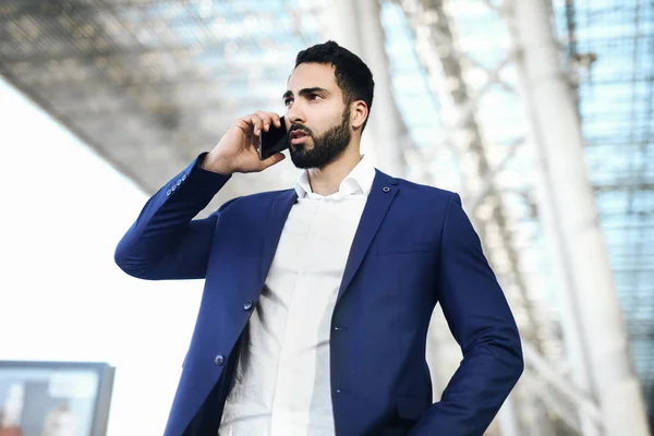 Airport man on smart phone at gate waiting in terminal. Air travel concept with young casual business woman sitting with talking on the smartphone, carry-on hand luggage trolley. Beautiful young.