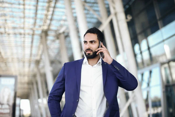 Airport man on smart phone at gate waiting in terminal. Air travel concept with young casual business woman sitting with talking on the smartphone, carry-on hand luggage trolley. Beautiful young.