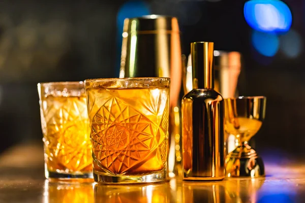 Üç renkli kokteyller büyük gözlüklü bir klasik bar ortamı içinde belgili tanımlık geçmiş bulanık içki şişeleri düzinelerce.