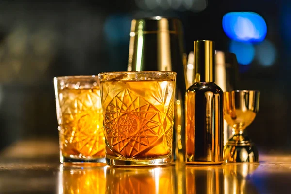 Üç renkli kokteyller büyük gözlüklü bir klasik bar ortamı içinde belgili tanımlık geçmiş bulanık içki şişeleri düzinelerce.