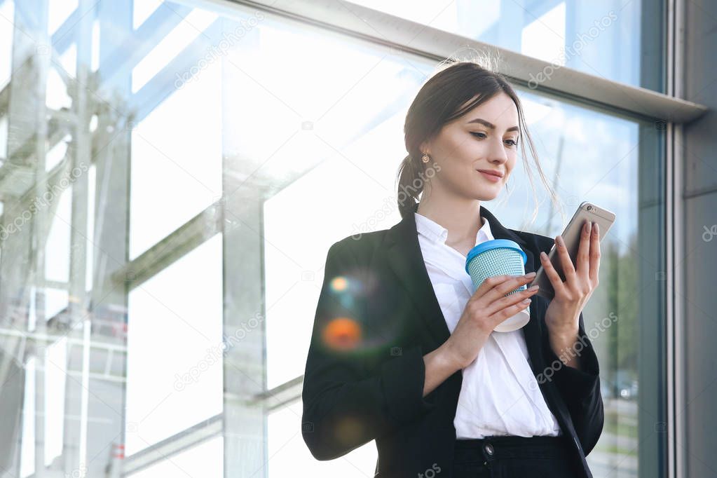 Business woman with coffe and talking on the phone near office