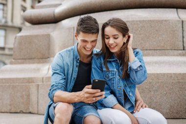 Çift veya komik gülen ve having fun bir akıllı telefon ile büyük bir şehirde sokak arkadaşlar