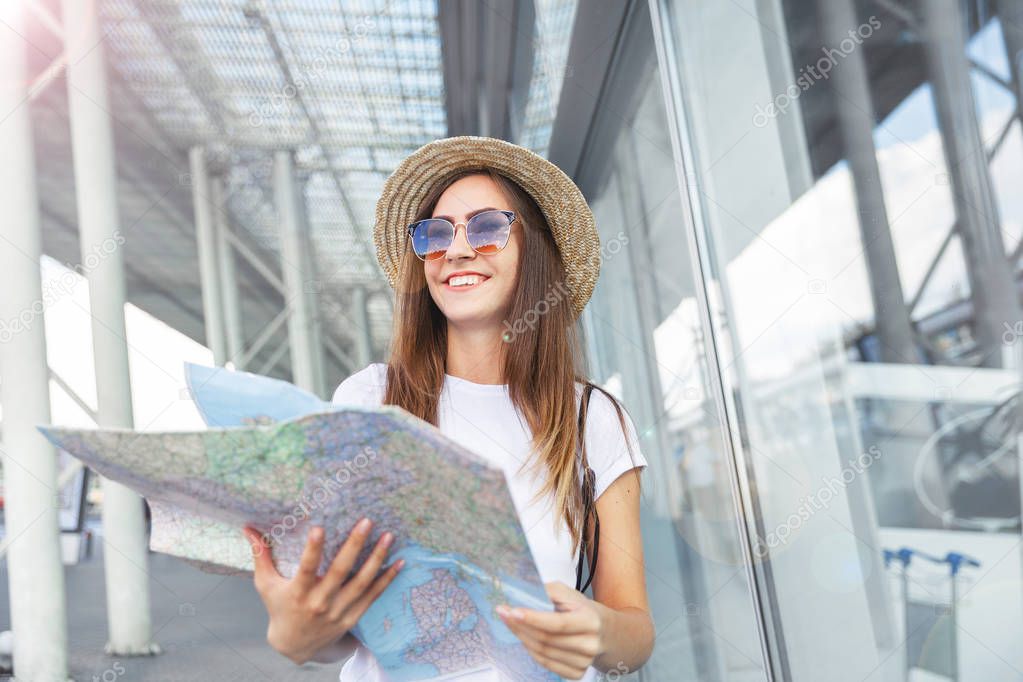 Young smiling  tourist at window  looking upwards with a map in her hand. bright o sunset light, traveling along Europe, freedom and active lifestyle concept