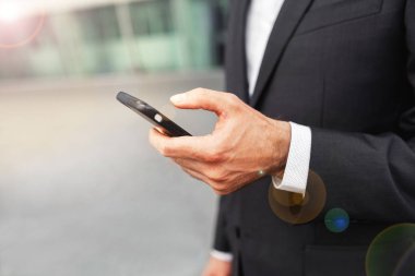 Mobil akıllı telefon kullanan bir adam kapatın. İş ve bilgi teknolojisi kavramı. şehir içinde belgili tanımlık geçmiş ile ayakta sokak