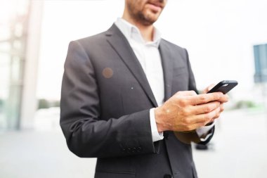 Mobil akıllı telefon kullanan bir adam kapatın. İş ve bilgi teknolojisi kavramı. şehir içinde belgili tanımlık geçmiş ile ayakta sokak