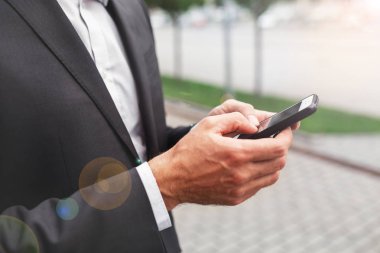 Mobil akıllı telefon kullanan bir adam kapatın. İş ve bilgi teknolojisi kavramı. şehir içinde belgili tanımlık geçmiş ile ayakta sokak