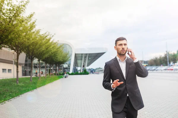 Joven Hombre Negocios Sonriente Hablando Por Teléfono Celular Caminando Cerca — Foto de Stock