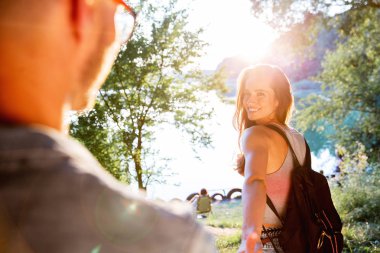 Yakışıklı adam ve esmer kız doğal zemin üzerine güzel bir sıcak gün batımı üzerinde yürüme. çocuk elini tutarak kız yol açar.