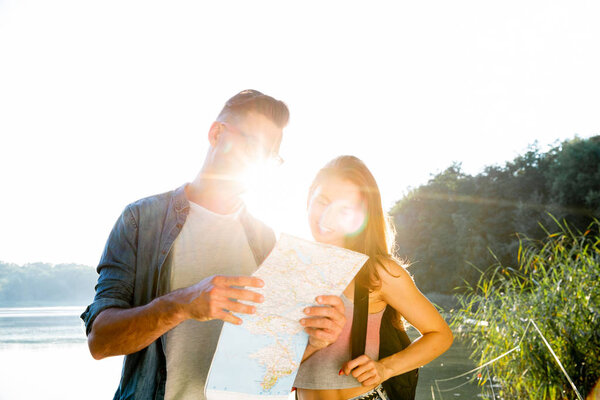 Young couple looking at map while on vacation during summer together. natural background. Relationships