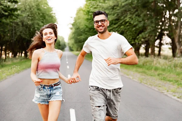 Happy Romantic couple running along the road against the background of the natural. Slow motio