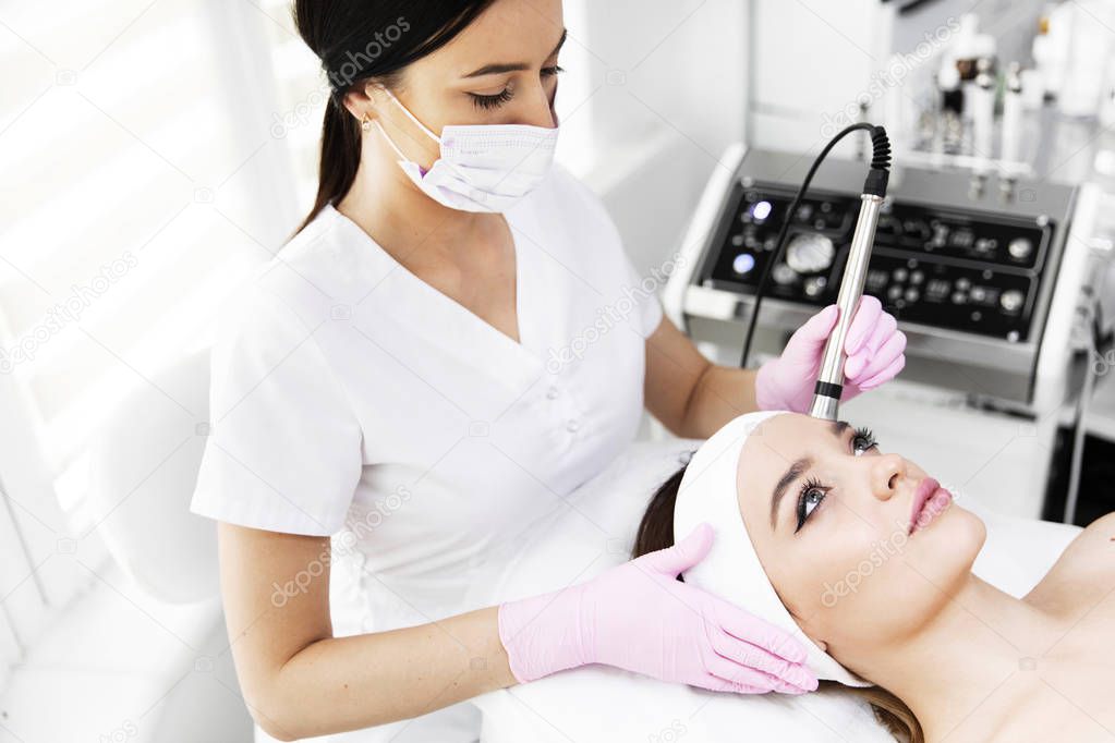 A woman came to laser hair removal facial. The woman lies and smiles, the doctor leads him in the face with a modern laser epilator. They are in the modern clinic.close up