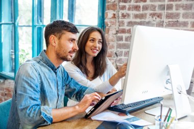 Güneşli ofis dizüstü bilgisayar üzerinde çalışan iki genç arkadaşları. Kağıt belgeleri holding ve defter ekranda gösteren kadın. Horizontal.Blurred background.startu