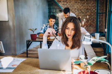 Genç sakallı işkadını kot gömlek Office masada oturuyor ve çizelgeler, grafikler ve diyagramlar üzerinde ekran ile laptop kullanıyor. Adam working.startu