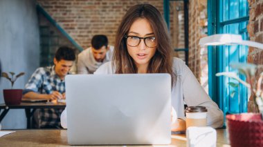 Genç sakallı işkadını kot gömlek Office masada oturuyor ve çizelgeler, grafikler ve diyagramlar üzerinde ekran ile laptop kullanıyor. Adam working.startu