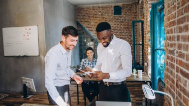 Yaratıcı proje üzerinde birlikte çalışıyor. İki emin iş adamları rahat içinde birlikte masada oturan ve bir şey tartışırken giymek. startu