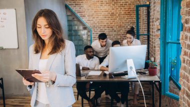Ofiste arkasında ekibi ile tablet kullanarak rahat iş kadını. başlangıç
