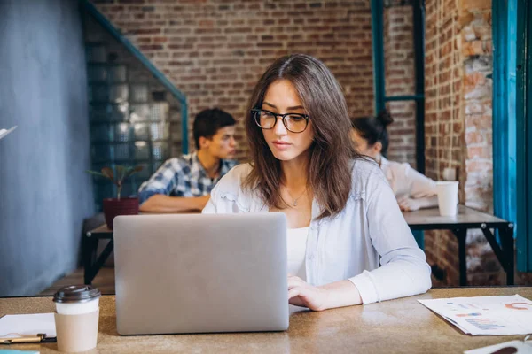 Genç sakallı işkadını kot gömlek Office masada oturuyor ve çizelgeler, grafikler ve diyagramlar üzerinde ekran ile laptop kullanıyor. Adam working.startup
