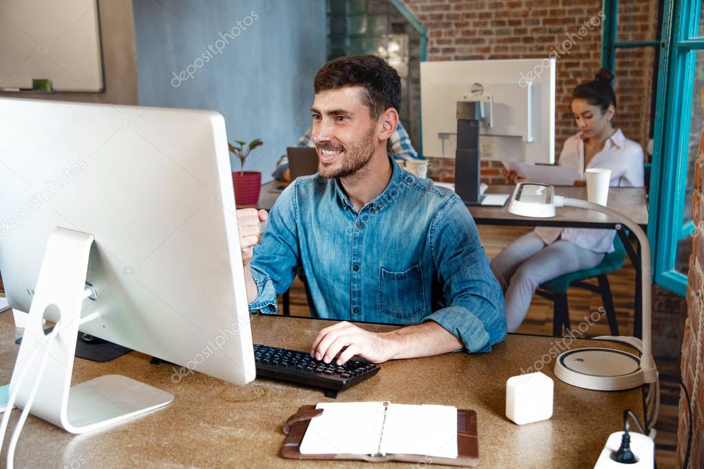 young man celebrate success at work pointing on his laptop. startu