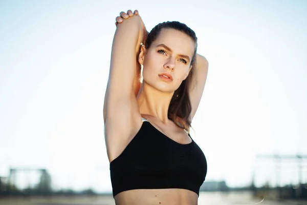 Gündoğumu ile güneşin içinde belgili tanımlık geçmiş vasıl uzanan bir fitness kadın profili silüeti. Açık havada kadar ısınma sağlıklı genç bir kadın. O onun kol ve bacak Germe.