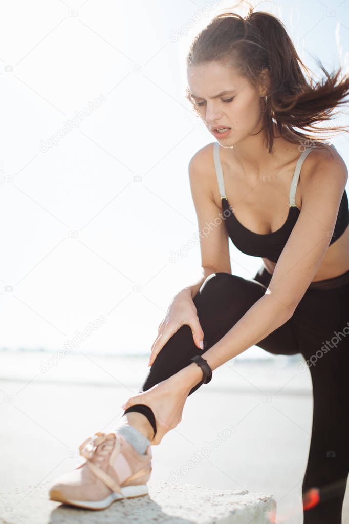 Woman hands on foot. She is feeling pain as his ankle or foot is broken or twisted. Accident on running track during the morning exercise. Sport accident and foot sprain concepts.