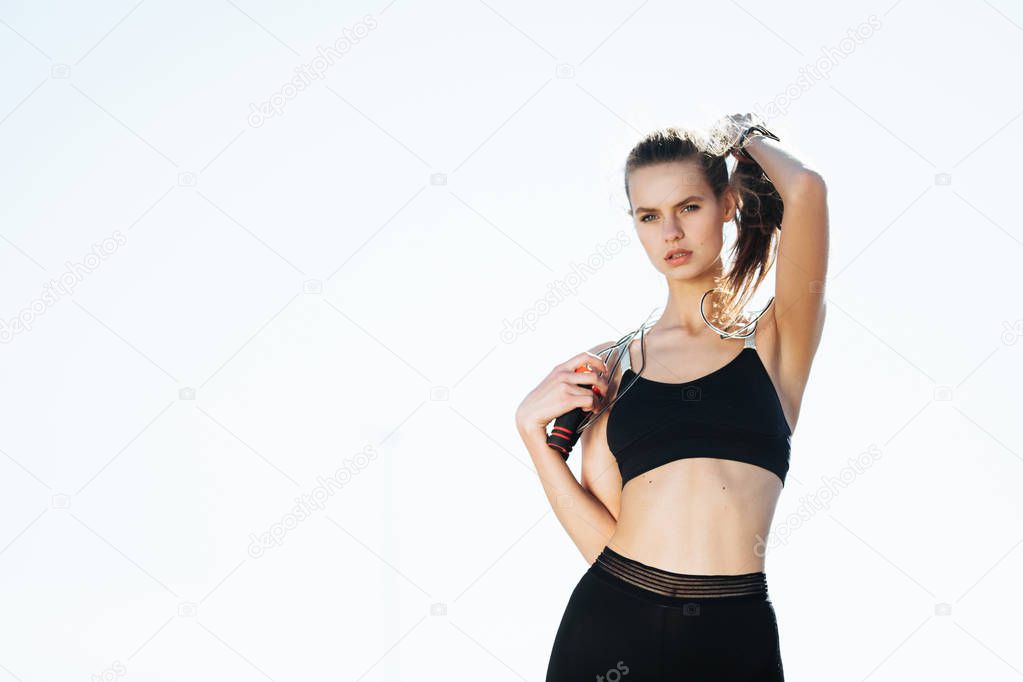 Tired fitness woman wipes sweat from forehead, feels fatigue after active cardio workout, does fitness exercise, has serious expression into distance