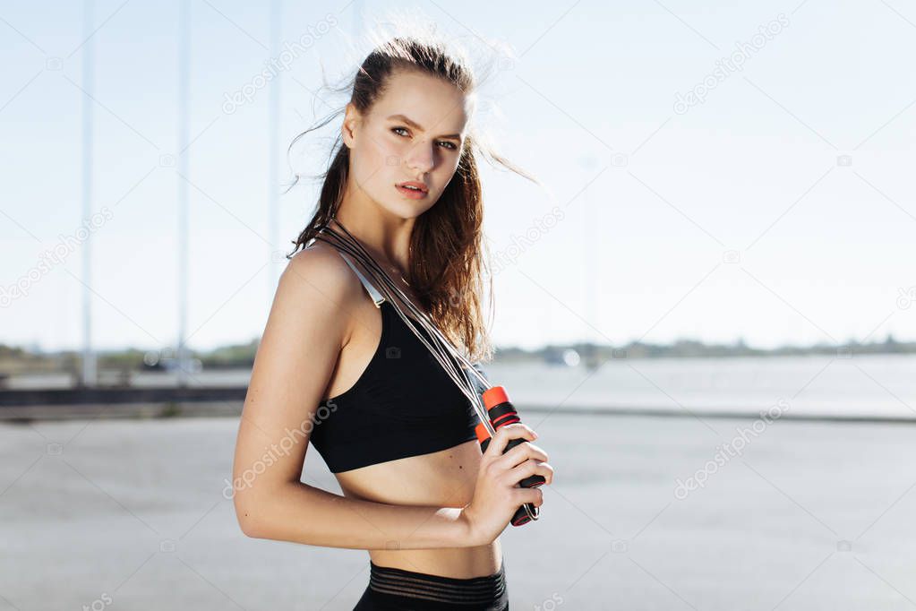 Tired fitness woman wipes sweat from forehead, feels fatigue after active cardio workout, does fitness exercise, has serious expression into distance