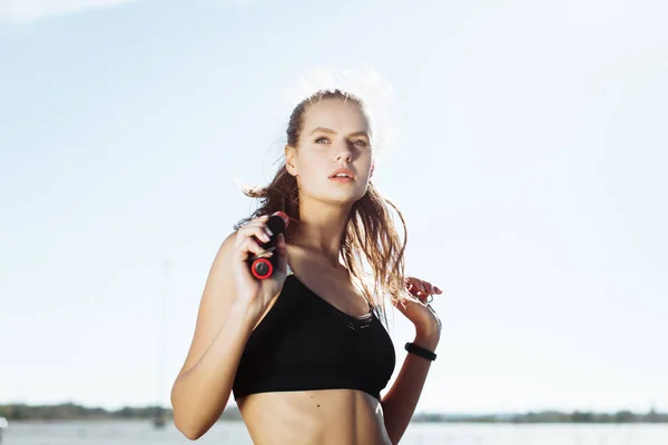 Tired fitness woman wipes sweat from forehead, feels fatigue after active cardio workout, does fitness exercise, has serious expression into distance