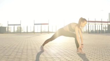 Gündoğumu ile güneşin içinde belgili tanımlık geçmiş vasıl uzanan bir fitness kadın profili silüeti. Açık havada kadar ısınma sağlıklı genç bir kadın. O onun kol ve bacak Germe.