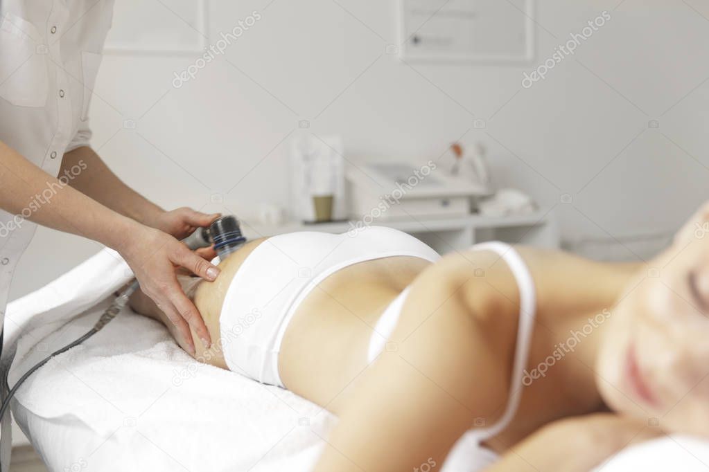 Body care. Close-up of beautiful long tanned woman legs receiving massage in spa salon. Skin care, wellbeing, wellness concept. Anti-cellulite spa treatment. Slender figure