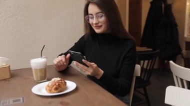 Beyaz gömlek giymiş ve modern akıllı telefon, cep telefonu dışında ağır çekim kısa mesaj yazarak profesyonel kadın işveren kullanarak güzel genç kadın