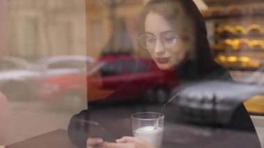 Beyaz gömlek giymiş ve modern akıllı telefon, cep telefonu dışında ağır çekim kısa mesaj yazarak profesyonel kadın işveren kullanarak güzel genç kadın