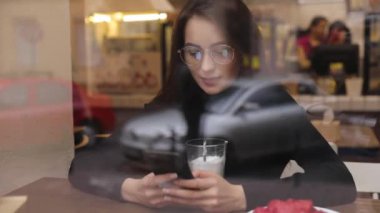 Beyaz gömlek giymiş ve modern akıllı telefon, cep telefonu dışında ağır çekim kısa mesaj yazarak profesyonel kadın işveren kullanarak güzel genç kadın