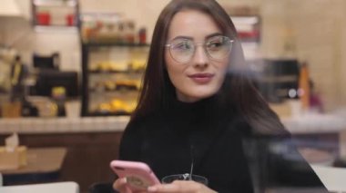 Beyaz gömlek giymiş ve modern akıllı telefon, cep telefonu dışında ağır çekim kısa mesaj yazarak profesyonel kadın işveren kullanarak güzel genç kadın