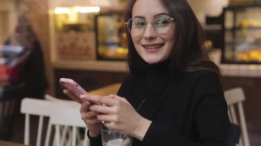 Beyaz gömlek giymiş ve modern akıllı telefon, cep telefonu dışında ağır çekim kısa mesaj yazarak profesyonel kadın işveren kullanarak güzel genç kadın
