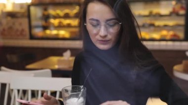 Beyaz gömlek giymiş ve modern akıllı telefon, cep telefonu dışında ağır çekim kısa mesaj yazarak profesyonel kadın işveren kullanarak güzel genç kadın