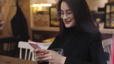 Beyaz gömlek giymiş ve modern akıllı telefon, cep telefonu dışında ağır çekim kısa mesaj yazarak profesyonel kadın işveren kullanarak güzel genç kadın